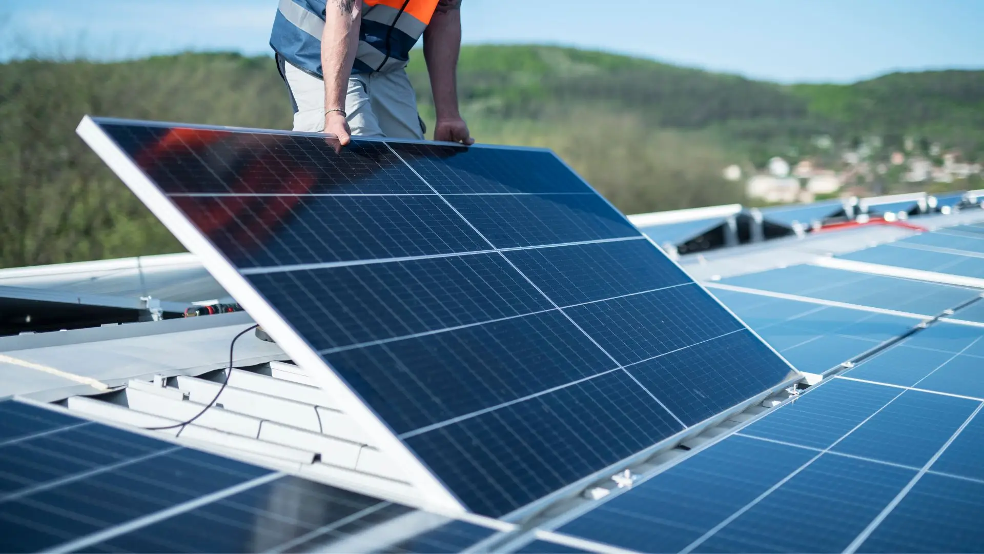 Immagine che mostra un uomo che sta posando un fotovoltaico sul tetto di una casa.